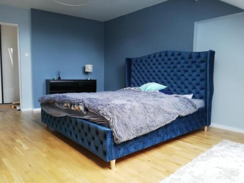 niebieskie łóżko z niebieskim zagłówkiem w sypialni w obiekcie Apartament Agiczar w mieście Giżycko