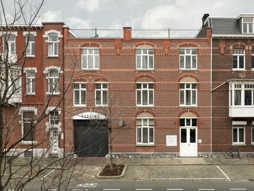ein großes rotes Backsteingebäude mit einer weißen Tür in der Unterkunft Townhouse Apartments Maastricht in Maastricht