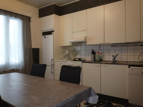 a kitchen with white cabinets and a table with chairs at Villa Keituri in Virrat