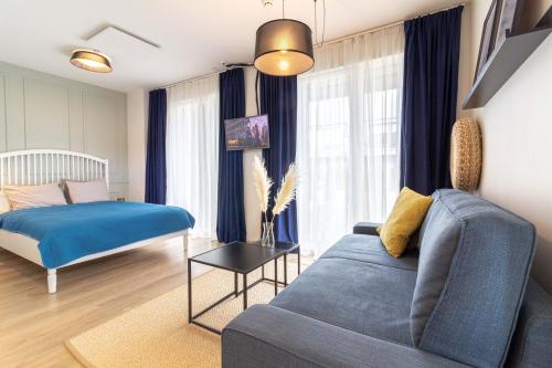 a living room with a blue couch and a bed at Green Shine Apartment, By Cohost in Palanga