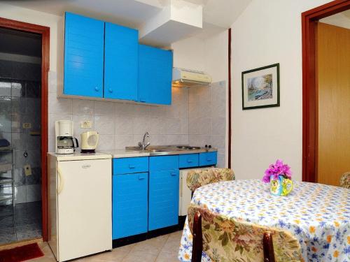 a kitchen with blue cabinets and a table with a table cloth at Apartments Mandica in Rabac