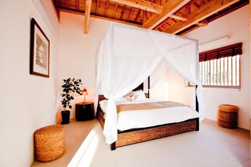 a bedroom with a bed with a mosquito net at Yamagata Ryukyu Hatago Onna Boukairou in Onna