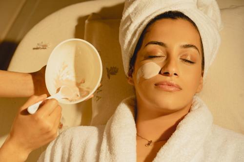 a woman getting her face moisturised with a towel at H Hotel & SPA - Adults Only in St Julian's