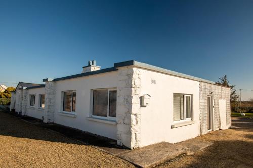 a white building sitting on the side of a road at Beachcomber Cottages in Ballyconneely