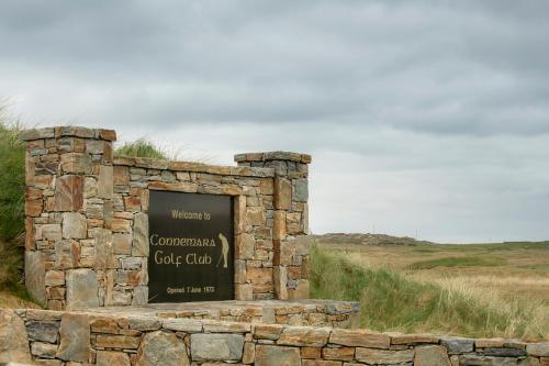 a stone building with a sign in a field at Beachcomber Cottages in Ballyconneely