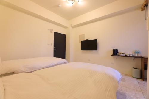two beds in a room with a tv on the wall at 七星潭118海景民宿 in Dahan