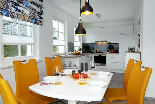 a kitchen with a white table and yellow chairs at Hirtenweg in Zingst