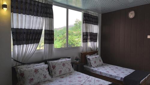a bedroom with two beds in front of a window at Lucky Star View Inn in Bandarawela