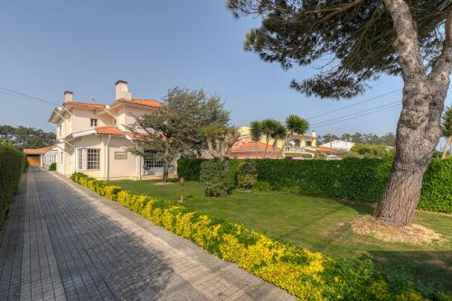 a white house with a tree and a sidewalk at Casa Do Norte in Ovar