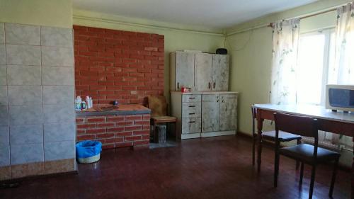 a kitchen with a brick wall and a table and a refrigerator at Dzīvoklis Pirmie Zaļmeži in Jūrkalne