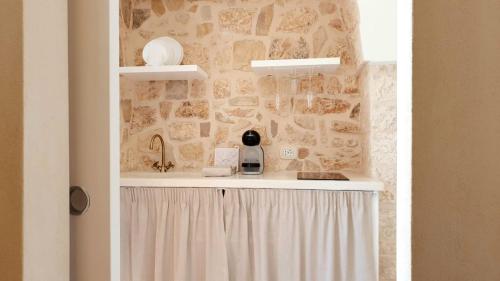 a bathroom with a sink and a stone wall at La Dimora del Colle in Fasano