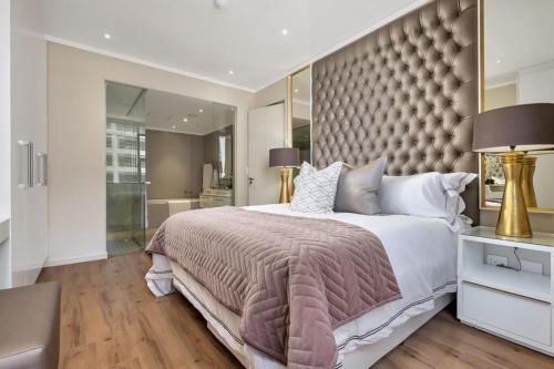 um quarto com uma cama grande e uma grande cabeceira. em Masingita Towers, 15 West Road South Road em Joanesburgo