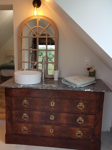 La salle de bains est pourvue d'un lavabo sur une commode et d'un miroir. dans l'établissement Au chant des oiseaux, à Le Torquesne