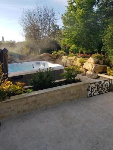 a hot tub in a garden with rocks at Au chant des oiseaux in Le Torquesne