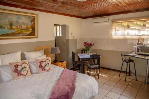 a bedroom with a bed and a table and a kitchen at Lincoln Cottages BnB & Self-Catering in Pietermaritzburg