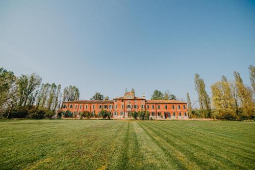 een groot bakstenen huis met een groot grasveld bij Tenuta Ca' Zen in Taglio di Po