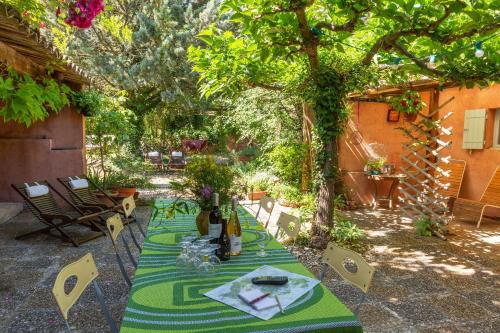 une table dans un jardin avec un tissu de table vert dans l'établissement Poterie de Pierroux, à Roussillon
