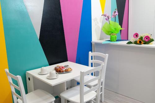 een tafel en stoelen in een kamer met een kleurrijke muur bij B&B Rainbow in Campofelice di Roccella