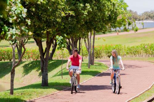 two people riding bikes down a path in a park at Blue Tree Thermas de Lins Resort in Lins