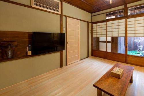 a living room with a flat screen tv and a table at Yamagata Kyomachihatago Kyotostation Mae in Kyoto