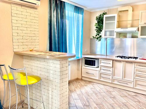 a kitchen with a counter and yellow chairs in it at Cozy studio in Vinnytsya