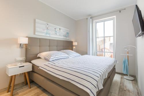 a white bedroom with a bed and a window at Whg 12 Viktoria Luna Ostseeflair in Zingst