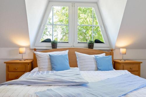 - un lit avec des oreillers bleus et blancs et une fenêtre dans l'établissement Alte Reihe 14 _Haus Teja_, à Zingst