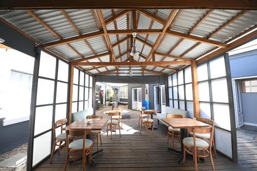 een restaurant met houten tafels, stoelen en ramen bij Wish U Were Here in Kaapstad