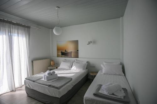 two beds in a white room with towels on them at Pharos Apartments in Gavrion