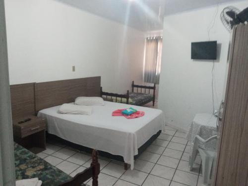 Hotel e Restaurante Recanto da Lagoa في لاغونا: غرفة نوم بسرير وكرسيين وتلفزيون