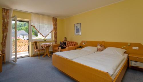 a hotel room with a bed and a woman sitting in a chair at Landhaus Schend in Immerath