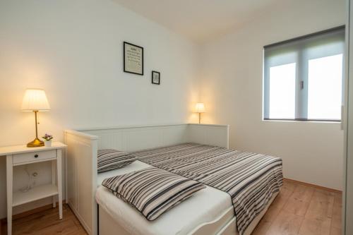 a white bedroom with a bed and a window at Kamp Mara in Pakoštane