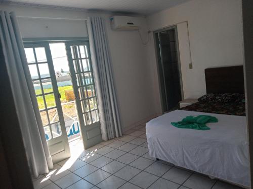 1 dormitorio con cama y vistas a un balcón en Hotel e Restaurante Recanto da Lagoa en Laguna