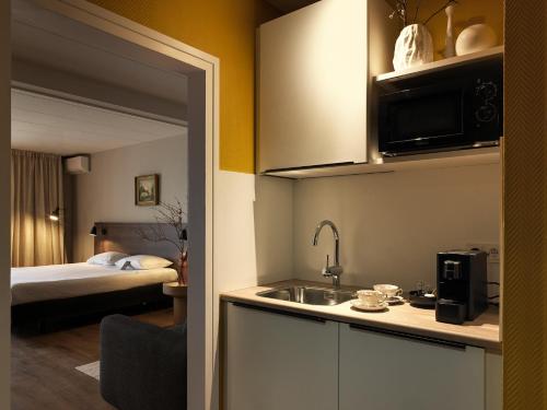 a kitchen with a sink and a room with a bed at Townhouse Maastricht & Spa in Maastricht