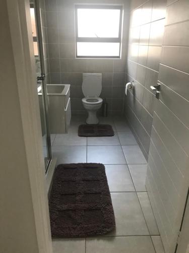 a bathroom with a toilet and a window and a rug at The blyde Pretoria unit 1244 in Pretoria