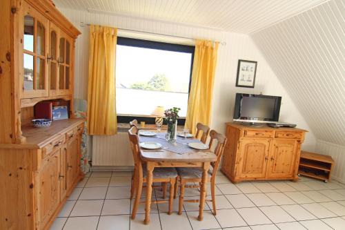 eine Küche mit einem Tisch mit Stühlen und einem TV in der Unterkunft Eva in Westerland
