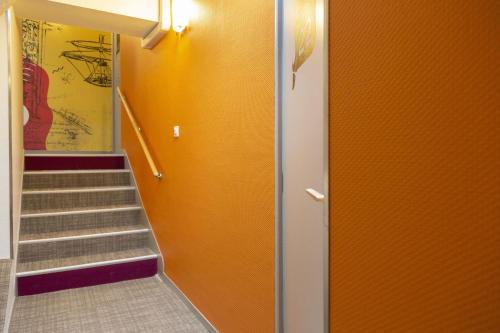 a hallway with a staircase with orange walls at Logis Hôtel Chaptal, Amboise in Amboise