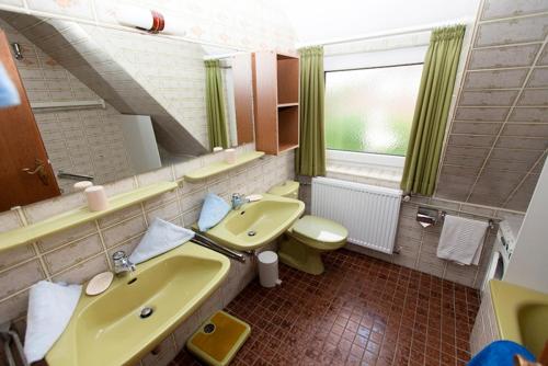 La salle de bains est pourvue d'un lavabo jaune et de toilettes. dans l'établissement Strandiris, à Wenningstedt