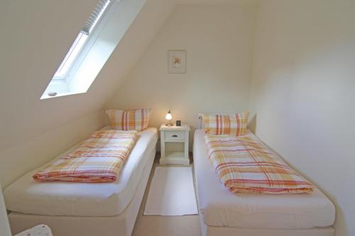 a attic room with two beds and a window at Sünje in Westerland