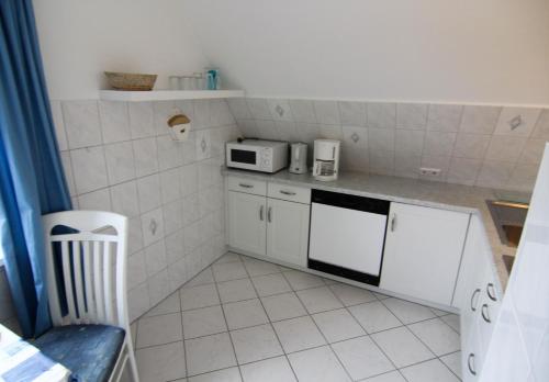 uma pequena cozinha com um micro-ondas e um fogão em Blaue Huis em Wenningstedt
