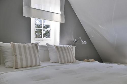 a white bed with white pillows and a window at Nelle 1 Stock in Wenningstedt