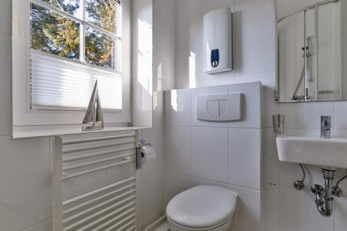 a white bathroom with a toilet and a sink at Nelle 1 Stock in Wenningstedt