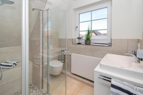 a bathroom with a shower and a toilet and a sink at Sylt Liebe in Wenningstedt