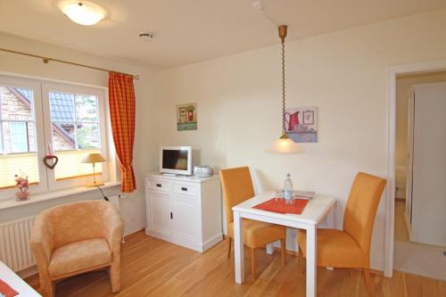 a living room with a table and chairs and a tv at Ose in Wenningstedt