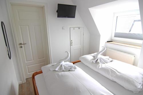 2 witte bedden in een kamer met een raam bij Osten in Westerland
