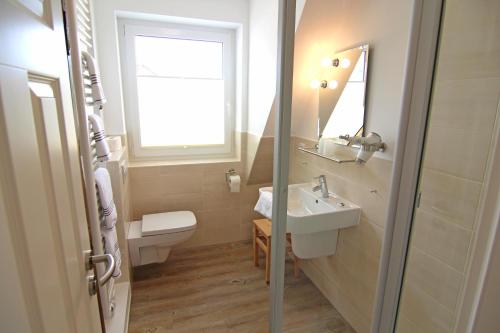 een badkamer met een wastafel, een toilet en een raam bij Osten in Westerland