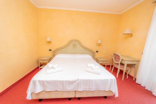 a bedroom with a white bed and two desks at Hotel Della Torre in Stresa