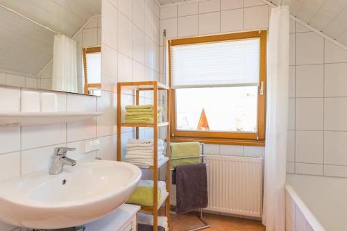 a bathroom with a sink and a shelf with towels at Ferienwohnung Lauser Dg in Herdwangen-Schönach