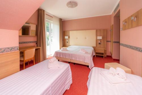 a hotel room with two beds and a window at Hotel Della Torre in Stresa