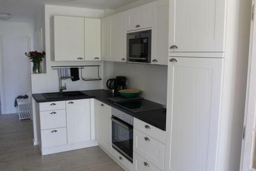 una cucina con armadi bianchi e piano di lavoro nero di Kavelweg 13 Kavella a Zingst